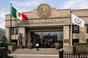 Edificio de juzgado con fachada de piedra, bandera de México y otra de justicia, estatua de la Dama de la Justicia, y personas entrando por la puerta principal.