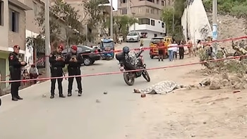 Policías custodian una calle acordonada con cinta roja donde yacen un cuerpo cubierto y una motocicleta policial