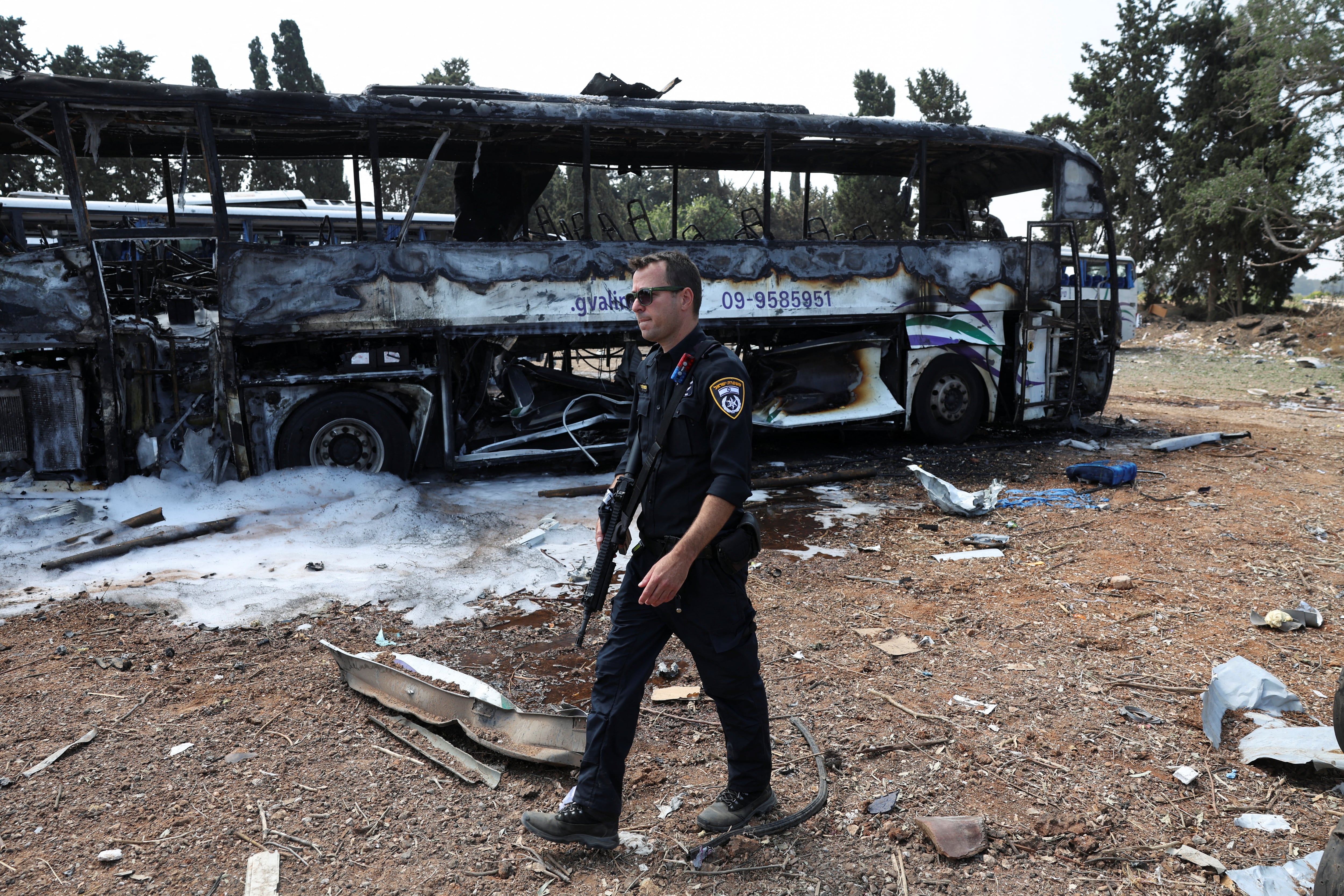 Un policía camina al lado de un autobus impactado por un misil que lanzó Irán contra la zona de Herzliya, (Tel Aviv, Israel)