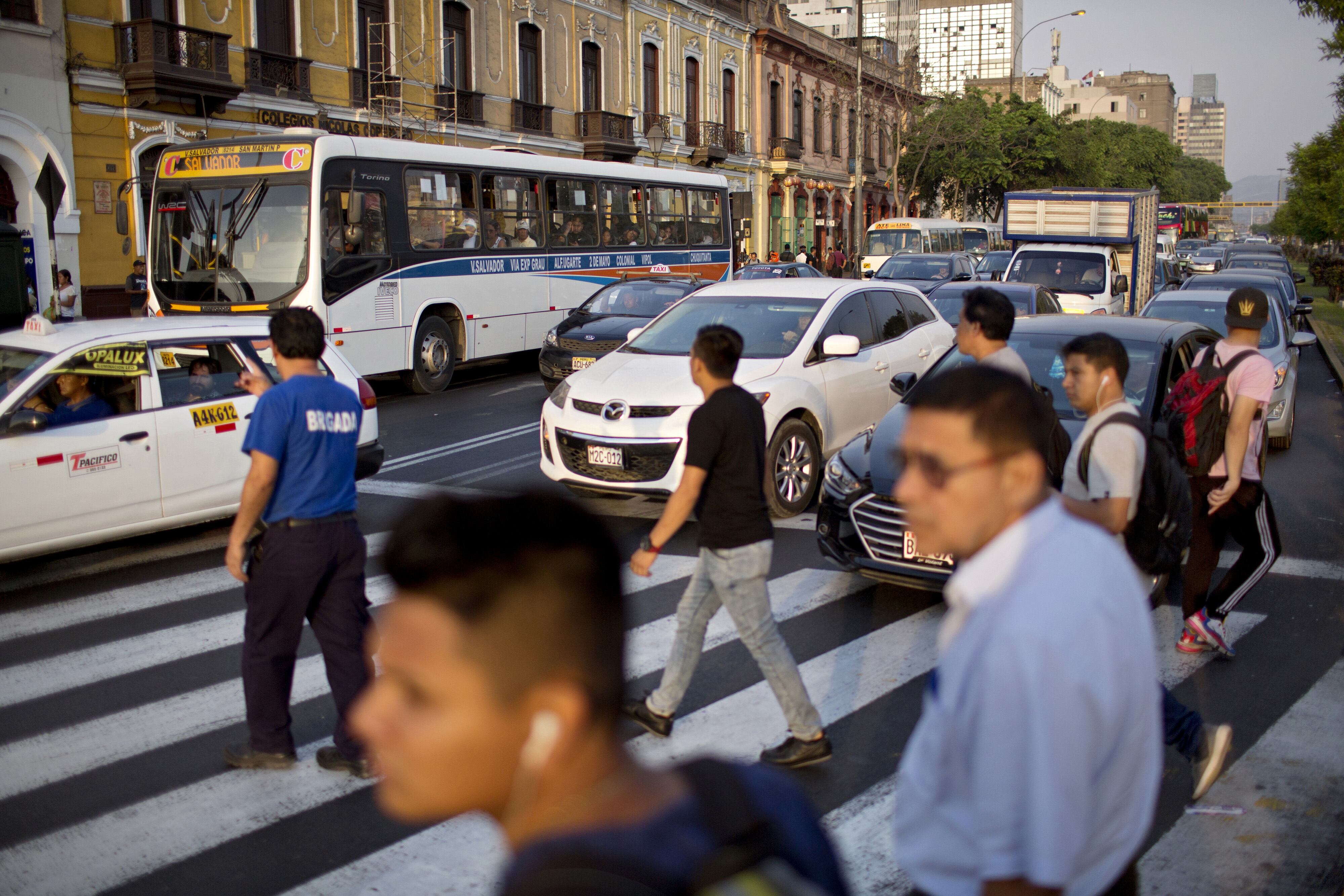 Pedestrians cross a street in front of traffic near Plaza Bolognesi in Lima, Peru, on Monday, Feb. 10, 2020. Peru