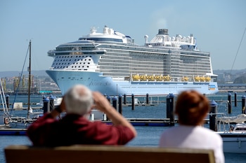 Un hombre observa con prismáticos al buque trasatlántico ‘Anthem of the Seas’, atracado en el puerto de A Coruña, en una imagen de archivo. (M. Dylan / Europa Press)