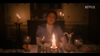 Una mujer joven sostiene una vela encendida en una mesa con copas y una jarra, junto a otras velas y un logotipo de Netflix