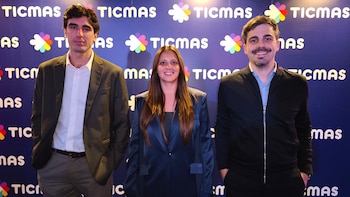 Sergio Siciliano, Lic. Florencia Casabella y un hombre sonríen de pie frente a una pared azul con logotipos blancos y coloridos de 'TICMAS'