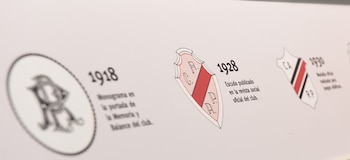 Vista de una exhibición en el Museo River mostrando la evolución de los escudos del club, incluyendo un monograma de 1918 y escudos de 1928 y 1930