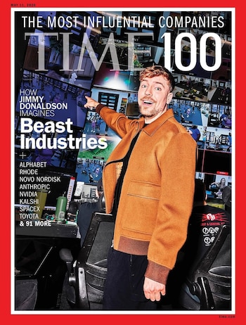 Mr. Beast sonríe en la portada de la revista TIME 100, con una chaqueta marrón, señalando pantallas que muestran múltiples videos de un entorno de estudio