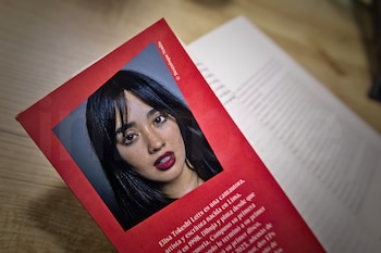 Un primer plano en ángulo picado del libro Borderline Sagrada sobre una mesa de madera clara. Se muestra la contraportada roja con la fotografía en blanco y negro de la autora Elisa Tokeshi y una breve biografía.