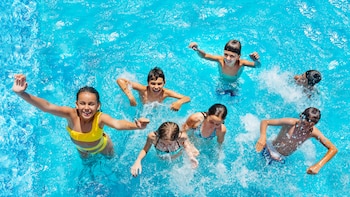 Varios niños jugando en una piscina y pasándolo bien