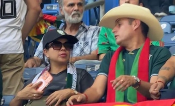 Primer plano de Diana Romero con gorra y gafas de sol, junto a Edmand Lara con sombrero vaquero y bufanda. Rodrigo Paz Pereira se ve en el fondo