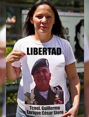 Una mujer sostiene una camiseta blanca con la palabra Libertad, la imagen de un militar y el texto Tcnel. Guillermo Enrique César Siero