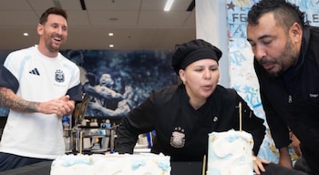 Lionel Messi sonriendo y aplaudiendo junto a Antonia Farías y Diego Iacovone. Farías sopla las velas de dos pasteles blancos