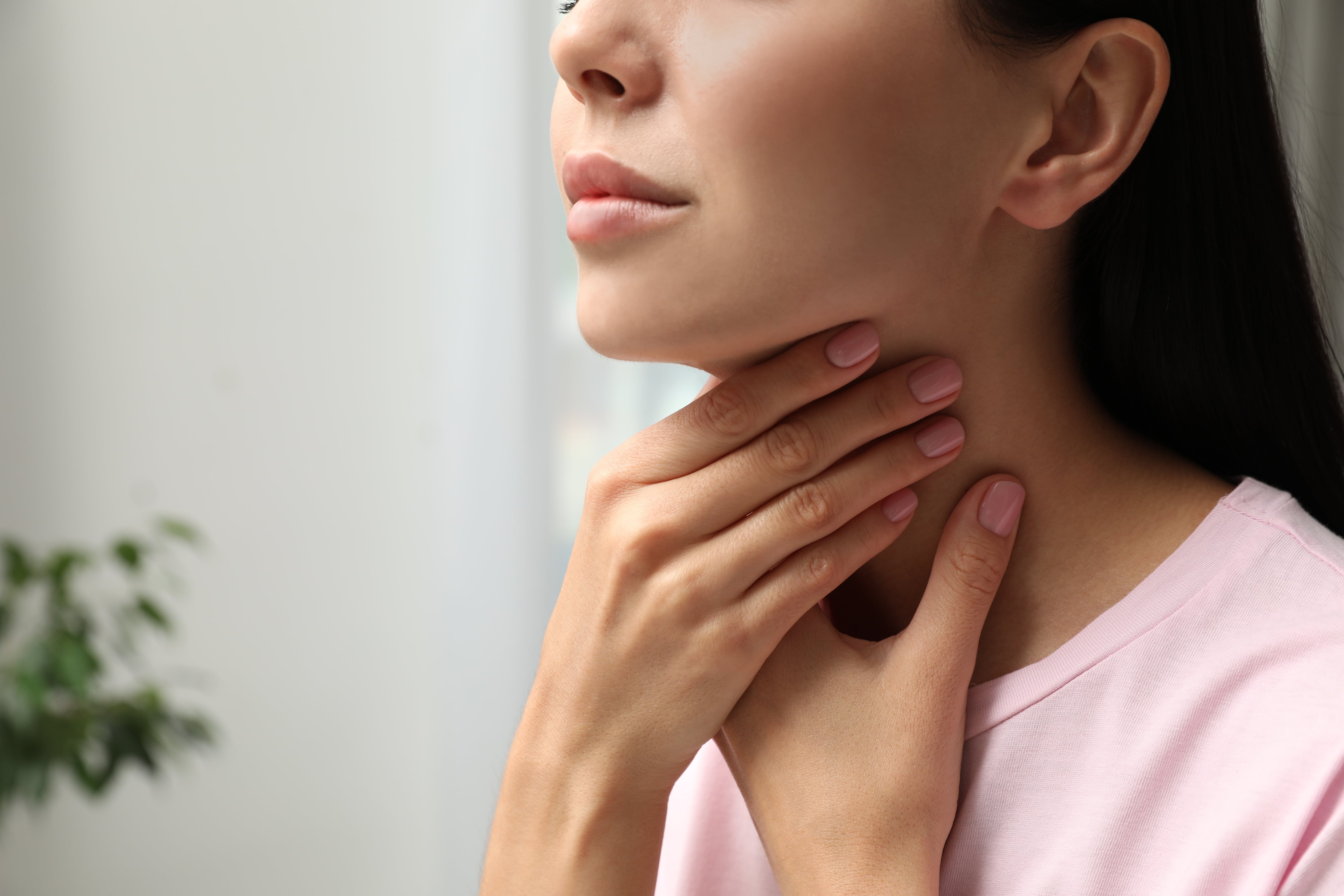 Una mujer examinándose los ganglios linfáticos del cuello (AdobeStock)