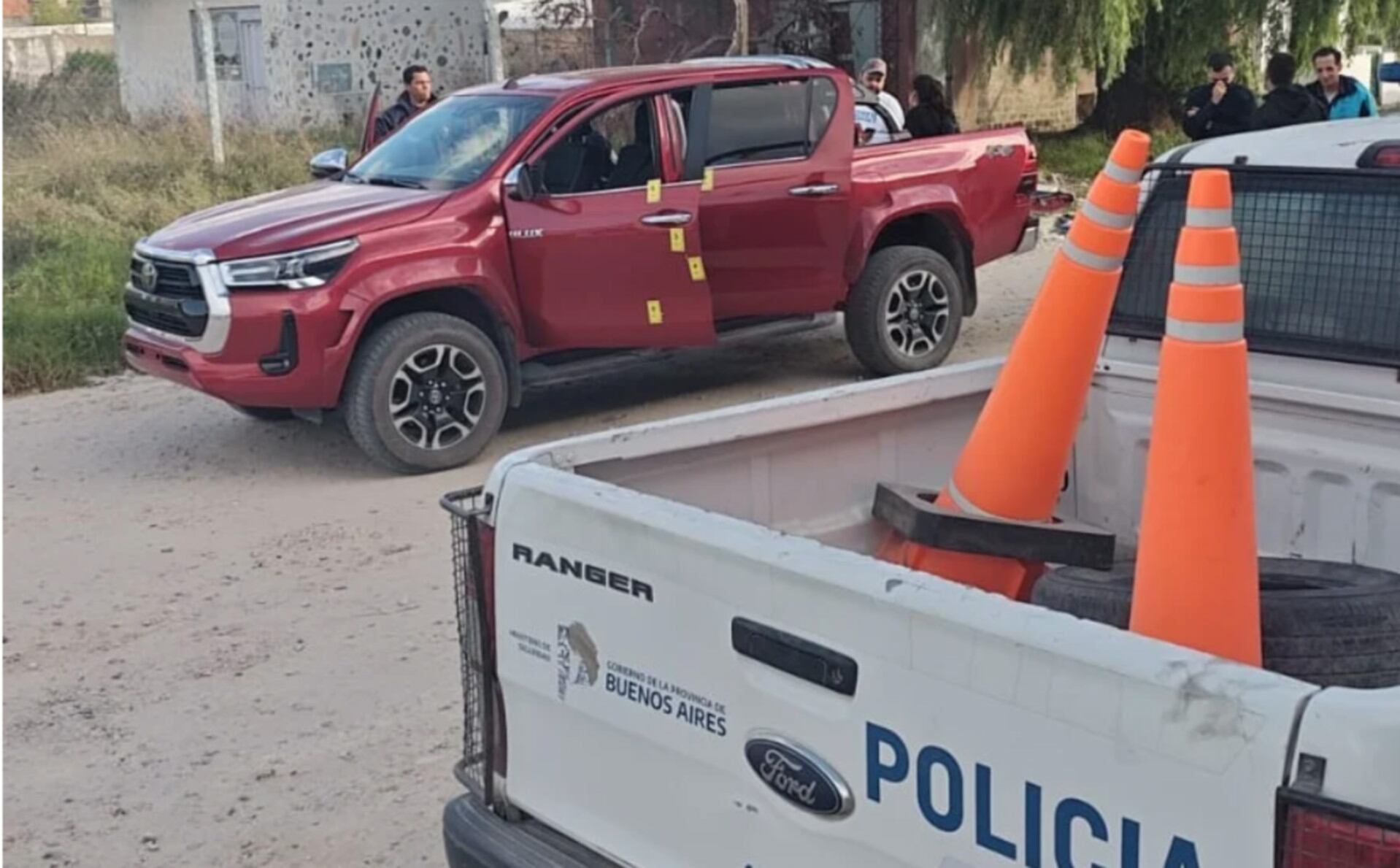 Oficiales de policía y equipos forenses inspeccionan una camioneta pickup roja con puertas abiertas y marcadores de evidencia después de que un hombre fuera baleado en Mar del Plata. (La Capital de Mar del Plata)
