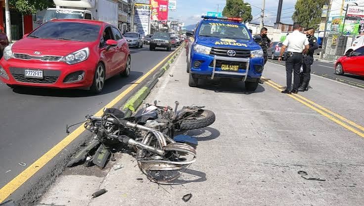 Una motocicleta yace en el suelo de una vía urbana, mientras un vehículo policial y agentes atienden la escena. (Redes Sociales)