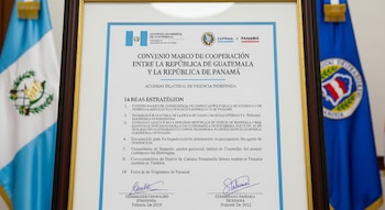 Un documento enmarcado titulado Convenio Marco de Cooperación entre la República de Guatemala y la República de Panamá, flanqueado por dos banderas.