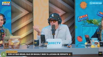 Mario Hart habla frente a un micrófono en un estudio con auriculares, gorra negra, gafas oscuras y un letrero de DIRECTV sobre la mesa