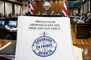 Expediente con 'Proyecto de Armonización del Mercado Eléctrico' y sello 'Aprobado en Primer Debate'. Al fondo, el hemiciclo de la Asamblea Legislativa de Costa Rica.
