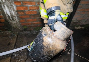 Un bombero retira un cilindro de gas doméstico tras las labores de extinción en la vivienda afectada por el incendio (Cortesía: Cuerpo de Bomberos).