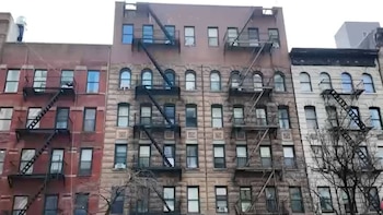 Fachada de varios edificios de apartamentos antiguos de ladrillo y piedra, con múltiples ventanas y escaleras de incendios exteriores en East Harlem