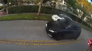 Imagen de dashcam muestra un carro deportivo negro avanzando junto a un autobús escolar con la señal de alto extendida, con otro auto blanco al fondo