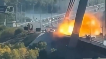 Una explosión con fuego y humo en la estructura de un puente por el que transitan varios automóviles