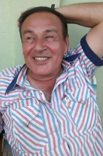 Retrato de Manubens Calvet, hombre de mediana edad con camisa a rayas rojas, blancas y azules, sonriendo con el brazo detrás de la cabeza