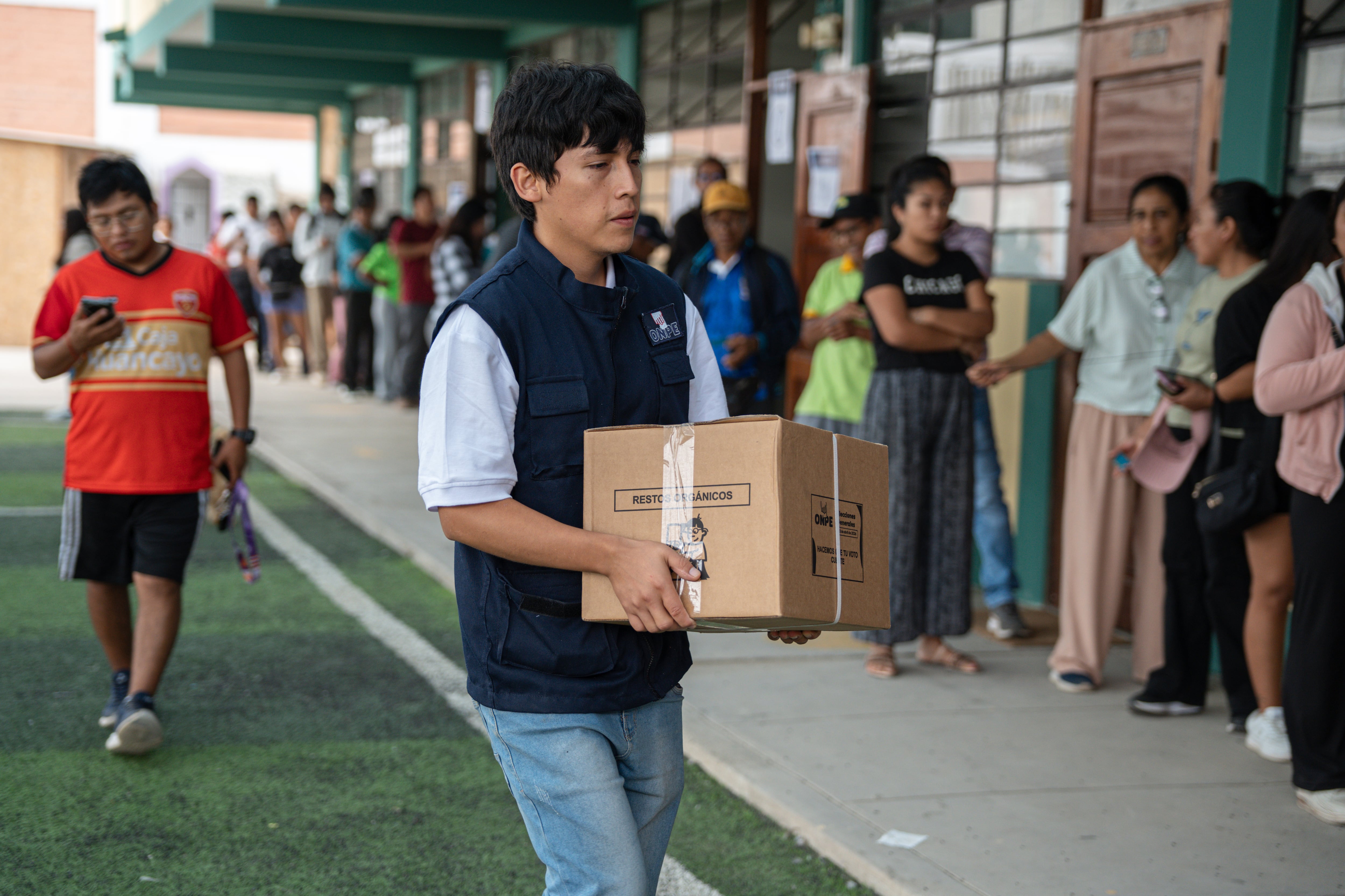 Fotografía del lunes 13 de abril de 2026 que muestra a un integrante de la Oficina Nacional de Procesos Electorales (ONPE) que carga una caja para empezar la instalación de una de las mesas de votación en el colegio Señor de los Milagros, en el distrito de Lurín (Perú). EFE/ John Reyes Mejía