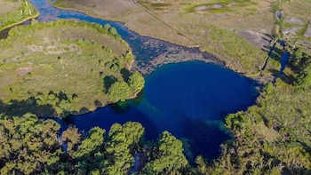Vista aérea de un lago azul profundo, un río serpenteante, y extensa vegetación verde en un paisaje natural