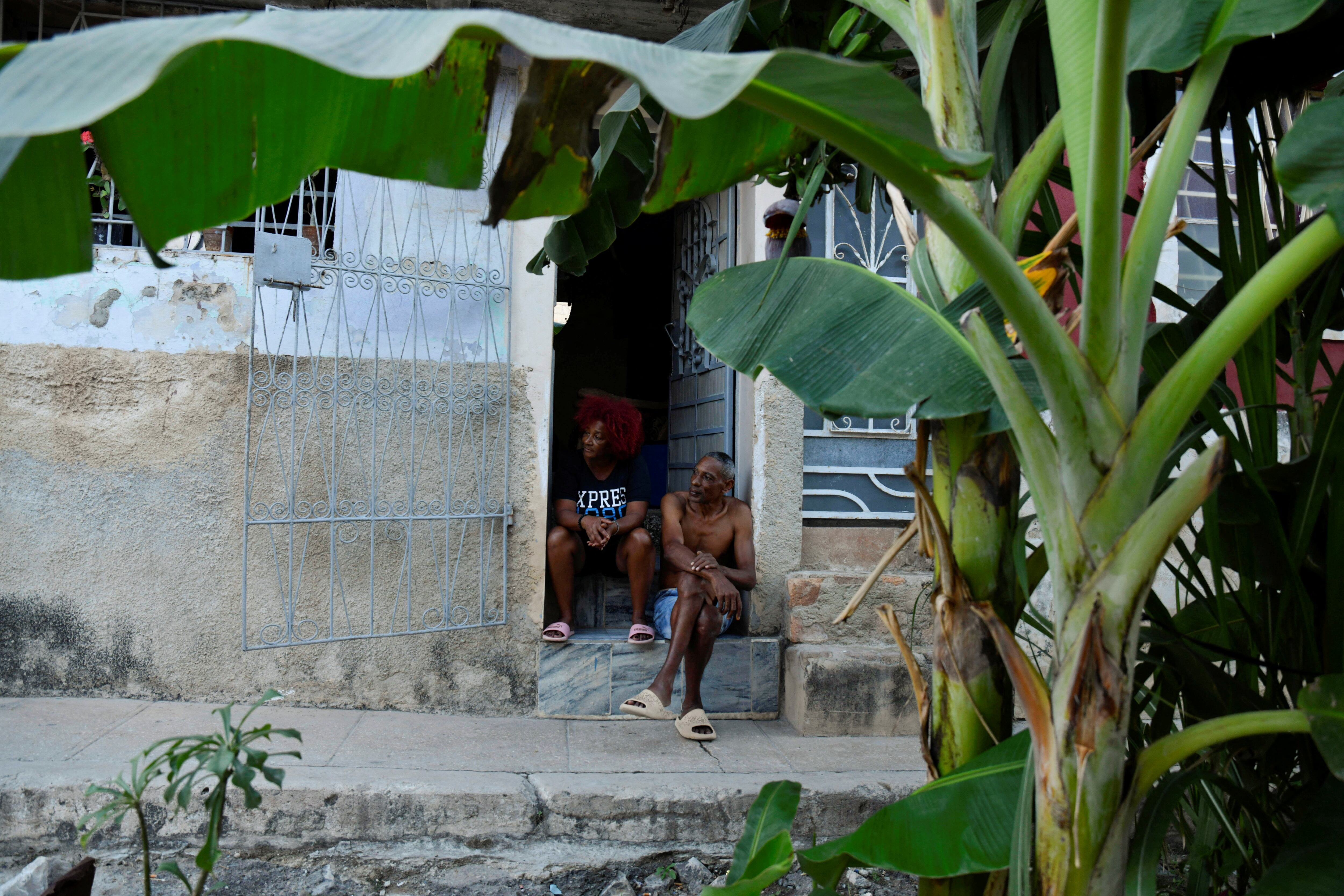 Carmen Guzmán y su esposo José Fleites conversan en la puerta de su casa, frente a plataneros que crecen en una calle de La Habana, Cuba, el 12 de febrero de 2025. REUTERS/Norlys Pérez