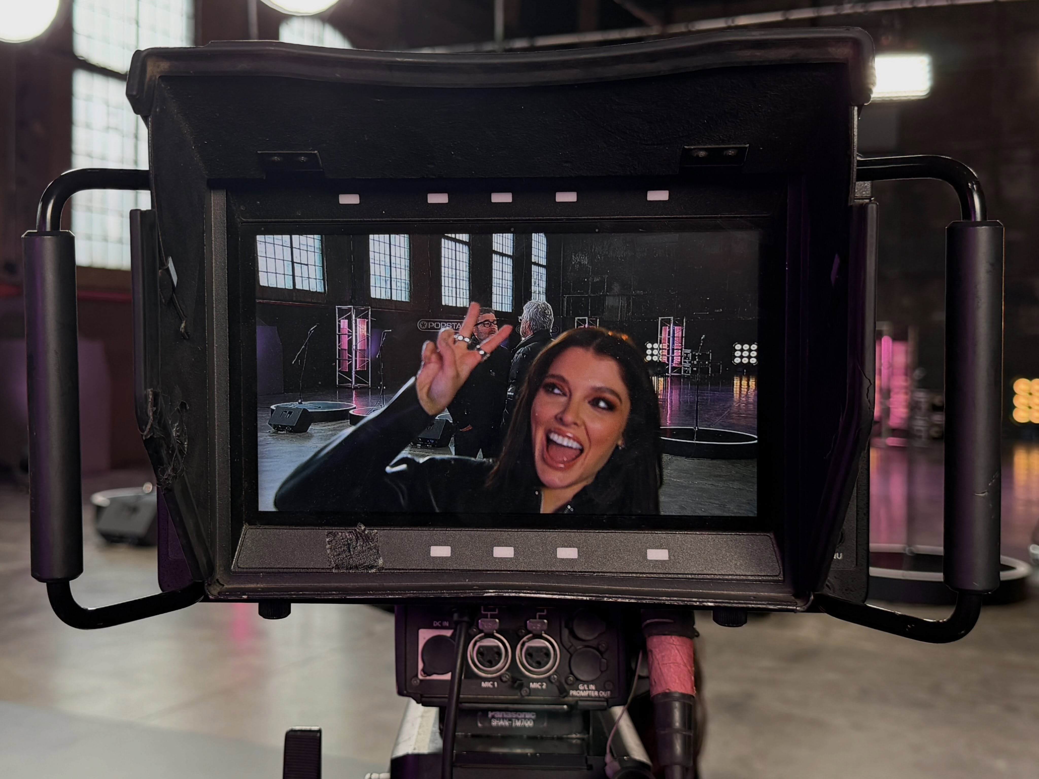 Sofi Gonet, confirmada como parte de Popstars, posa ante la cámara con un gesto de la mano visible en un monitor, en un set de estudio.