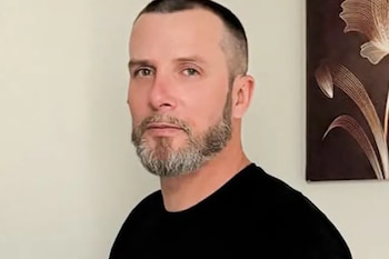 Retrato de Jay Glazer, un hombre con cabello oscuro corto y barba gris, vistiendo camiseta negra, mirando al frente sobre fondo claro con obra de arte