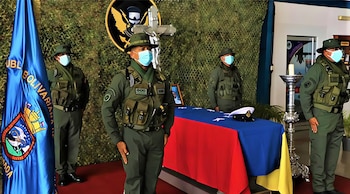 Cuatro militares uniformados, con mascarillas, rinden honores frente a un féretro cubierto con la bandera de Venezuela y una gorra naval