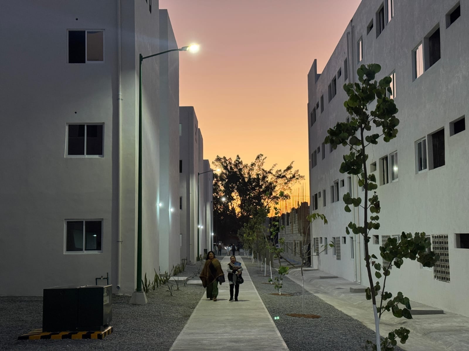 Residentes transitan por las nuevas Viviendas para el Bienestar en Chiapas al atardecer, destacando la infraestructura moderna y el entorno tranquilo de la comunidad.