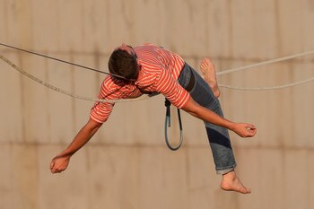 El funambulista francés Nathan Paulin recorre por un estrecho cable y en los dos sentidos los cerca de 350 metros que separan dos edificios entre la plaza Catalunya y el paseo de Gràcia, un espectáculo programado hoy domingo dentro del Grec Festival de Barcelona. EFE / Quique García.