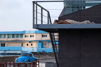 Un hombre amanece dormido en los accesos de una pasarela metálica, ante las altas temperaturas que registra el país. (Infobae Centroamérica/ YAMIL LAGE / AFP)