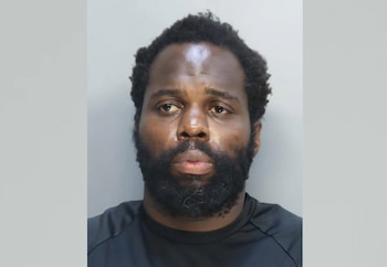 Fotografía policial de Wendy Louis, un hombre de barba corta y camiseta negra, sobre un fondo gris