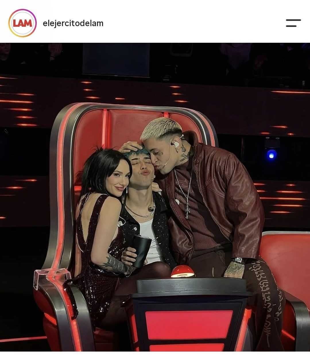 Los músicos La Joaqui, Tiago PZK y Luck Ra posan en un sillón rojo de escenografía durante una grabación.