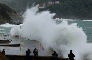 Turistas y donostiarras observan el fuerte oleaje que golpea el Paseo Nuevo de San Sebastián. (Juan Herrero/EFE)