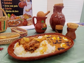 Plato de Sopa de Novios con arroz, piezas de pollo y salsa con fideos y huevo. Jarras y copas de cerámica, cestas de mimbre y un cartel de menú