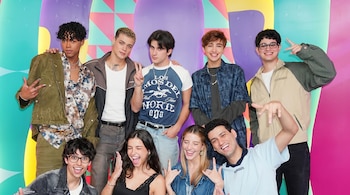 Miembros de Zaca TV y Santos Bravos posan sonrientes junto a otras personas frente a un fondo colorido y vibrante, haciendo gestos con las manos.