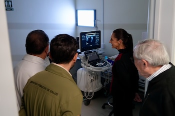 Claudia Sheinbaum y personal médico observan una pantalla de ecografía dentro de un consultorio hospitalario