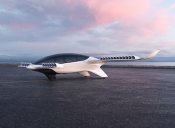 Primer plano de un avión futurista blanco y negro con múltiples hélices pequeñas, parado en una pista de asfalto con un lago y un cielo rosado al fondo