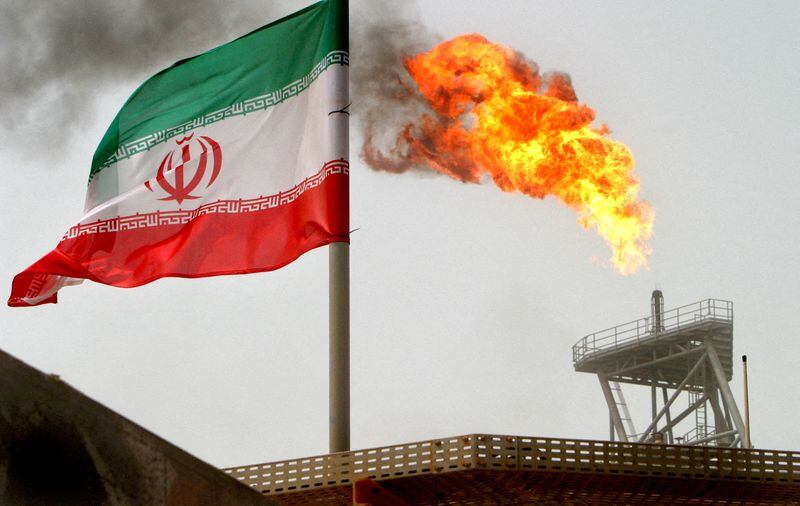 Una antorcha de gas en una plataforma de producción de petróleo junto a una bandera iraní en el Golfo (REUTERS/Raheb Homavandi/Archivo)