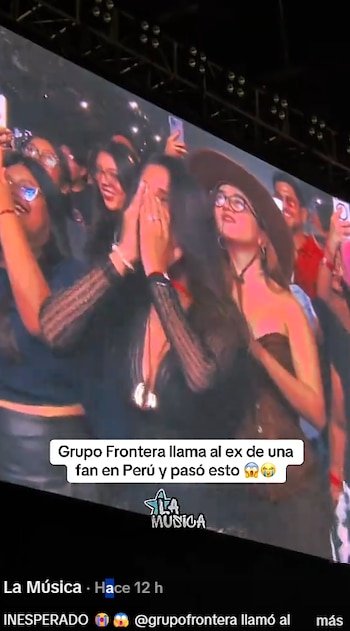 Pantalla de concierto que proyecta al público, con una mujer que se cubre la cara con las manos y un rótulo con texto en la parte inferior