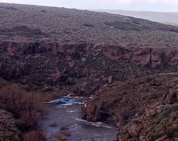 Dos personas observan una carpa médica inflable, una ambulancia y camionetas policiales en un terreno rural