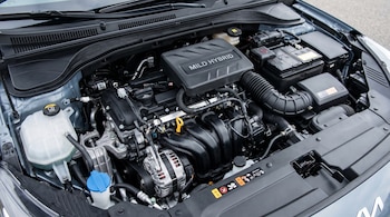 Vista superior del compartimento del motor mild hybrid de un automóvil, mostrando el motor, batería, depósitos de líquidos y diversas mangueras y cables.