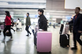 Travelers carry their luggage through