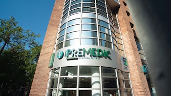 Edificio de ladrillo y vidrio con cartel de Grupo Premedic Medicina Privada, rodeado de árboles y con cielo azul