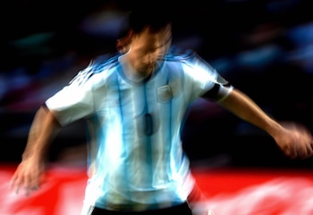 Hombre con camiseta de fútbol de Argentina con rayas celestes y blancas y el número diez, en movimiento borroso, sobre un fondo oscuro con tonos rojos