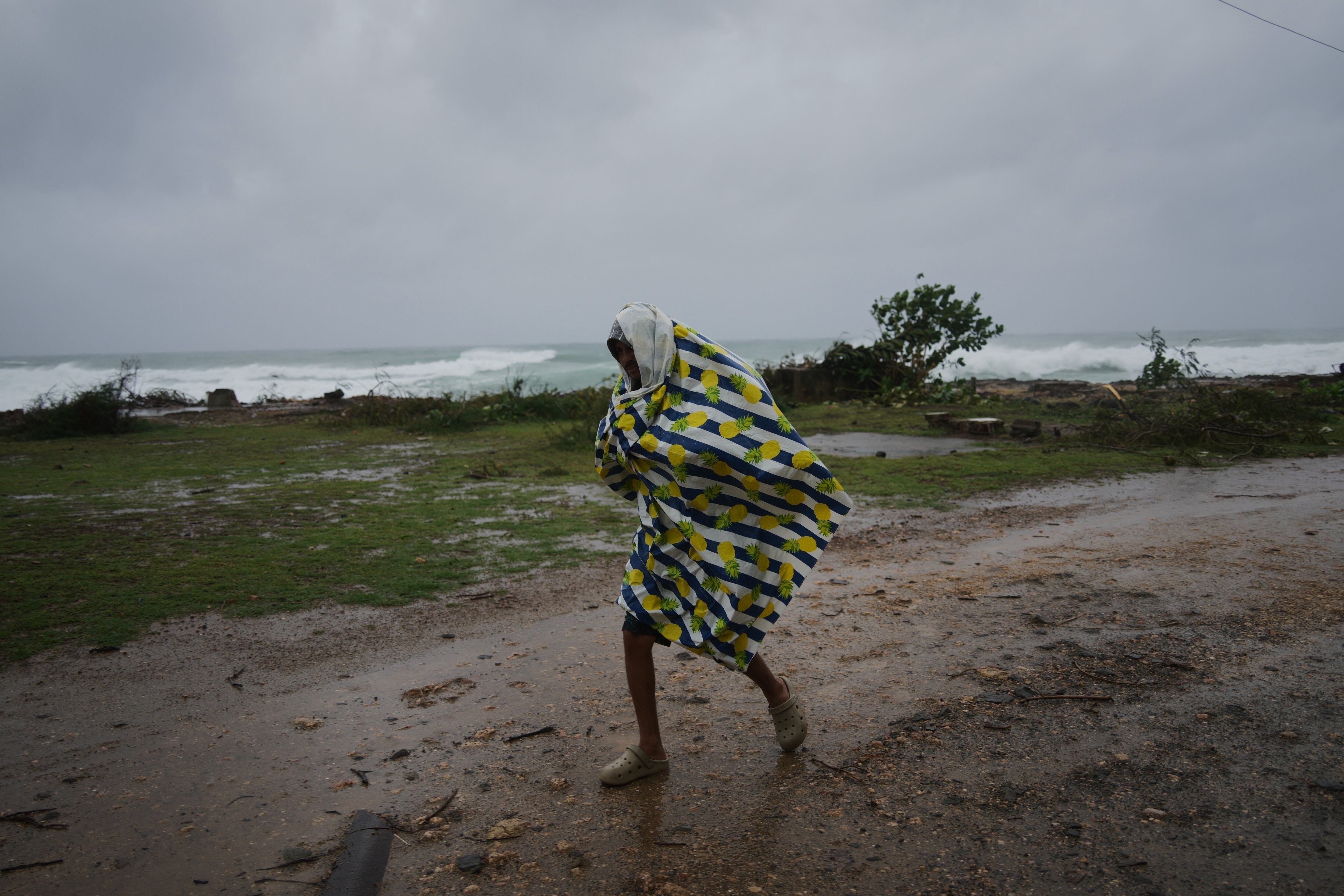Un hombre camina bajo la lluvia antes de la llegada del huracán Melissa, en Canizo, una localidad en Santiago de Cuba, el 28 de octubre de 2025. (AP Foto/Ramón Espinosa)