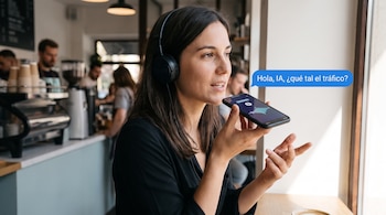 Una mujer con auriculares sostiene un teléfono móvil cerca de la boca junto a un mensaje flotante que pregunta sobre el tráfico.